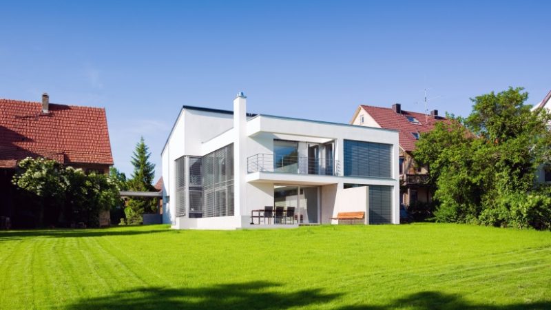 Weißer Neubau im Bauhausstil aus dem Garten fotografiert