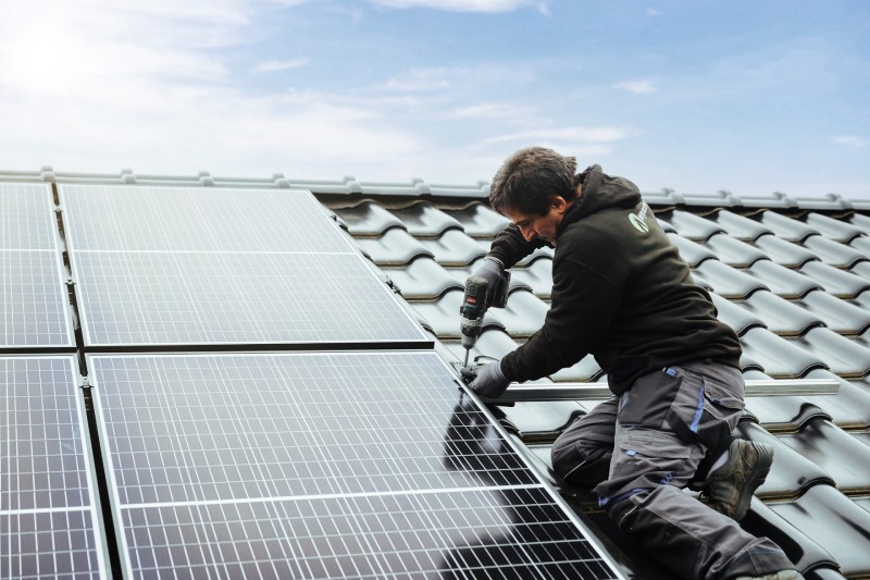 Handwerker bei der Mintage eines Solarmoduls auf Hausdach