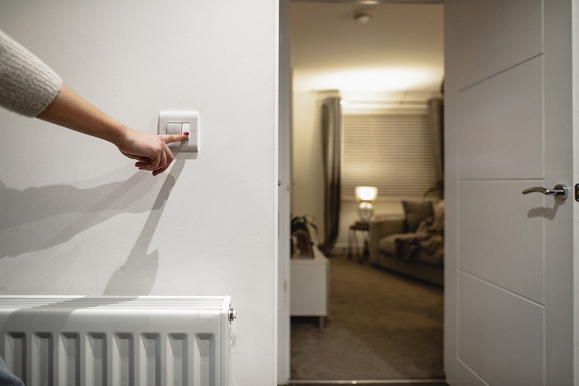 Mensch betätigt Lichtschalter im Haus