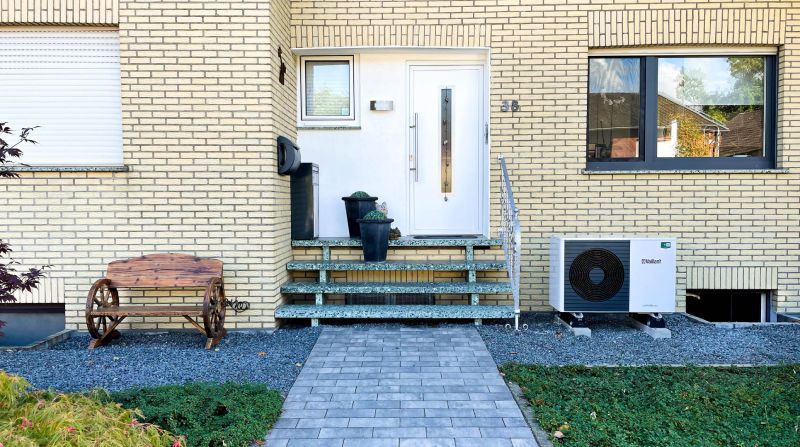 Vaillant atoTHERM plus Luftwärmepumpe vor Einfamilienhaus mit Garten im Vordergrund 