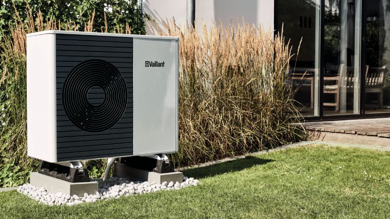 Vaillant Wärmepumpe im Sommer neben Terrasse eines Hauses 