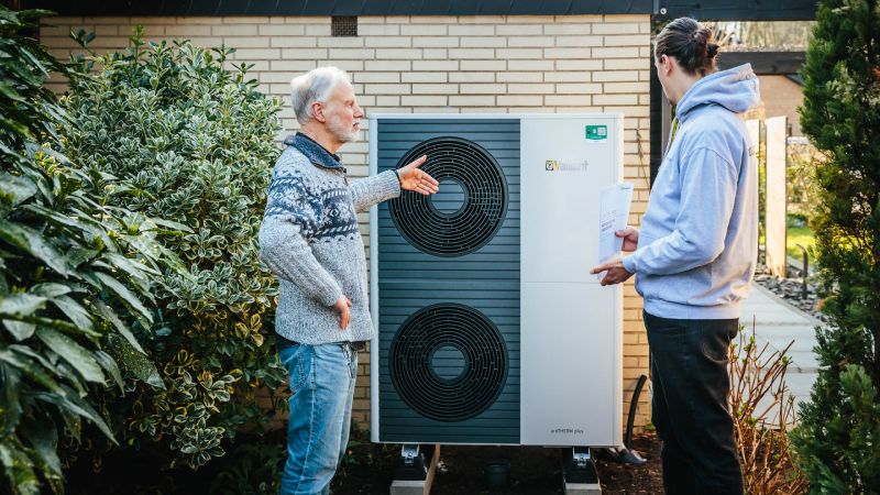 Zwei Männer stehen vor einer Vaillant Wärmepumpe hinter einem Haus